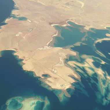 A window photo of turquoise reef and desert coast over the Red Sea