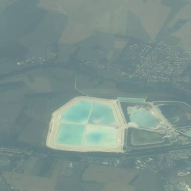 Flat farmland and mineral ponds through haze over northern Europe